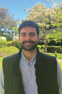 Smiling man wearing a button up shirt and vest standing outside