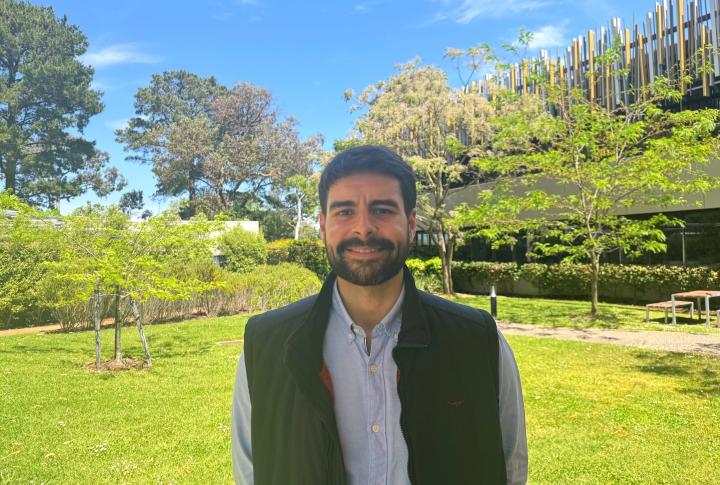 Man standing outside with trees and buildings behind