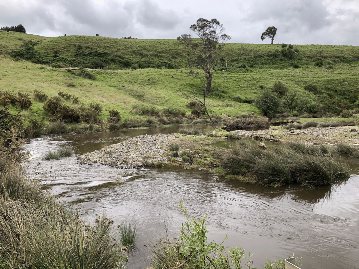 River surrounded by green rolling hills 