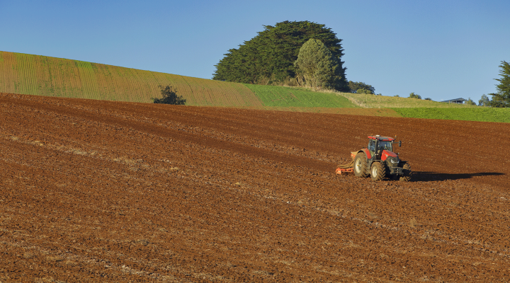 Tractor driving along a field on a sunny day