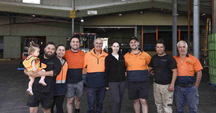 Group of people wearing work high vis, standing inside a large shed