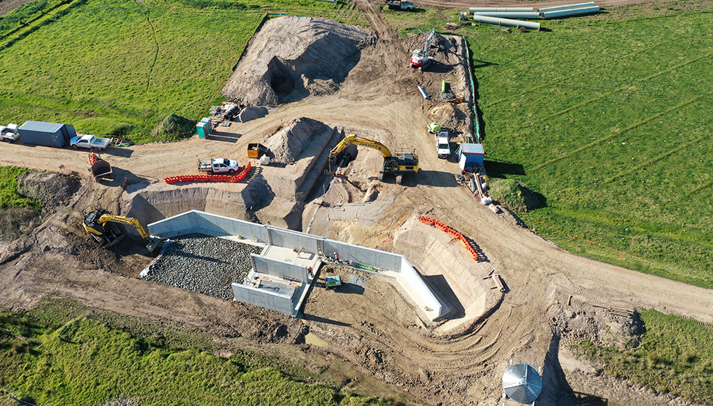 Birds eye image of construction vehicles in a field digging a hole